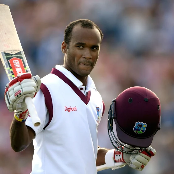 West Indies cricketer raising bat and holding helmet after scoring runs in a Test match