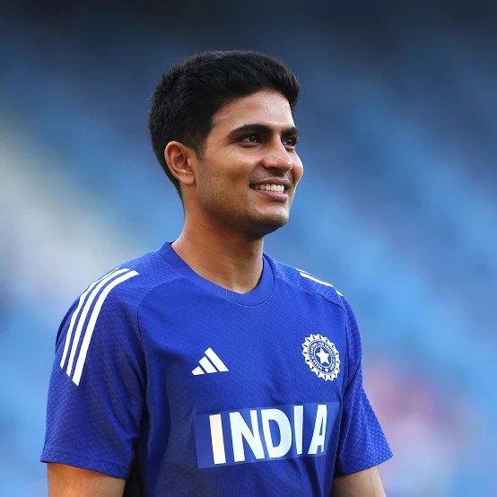 "Indian cricket player in blue jersey smiling during practice session.